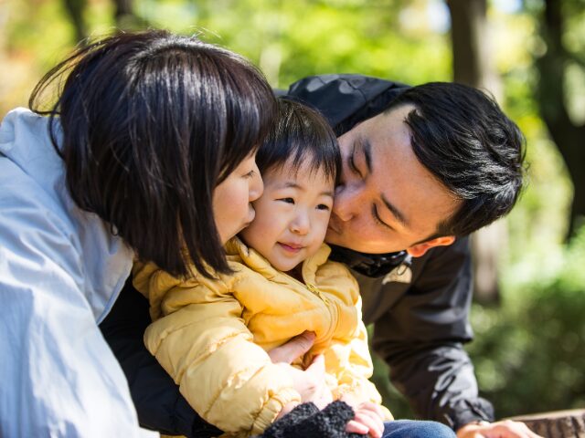 子どものほっぺにキスをしている女性と男性