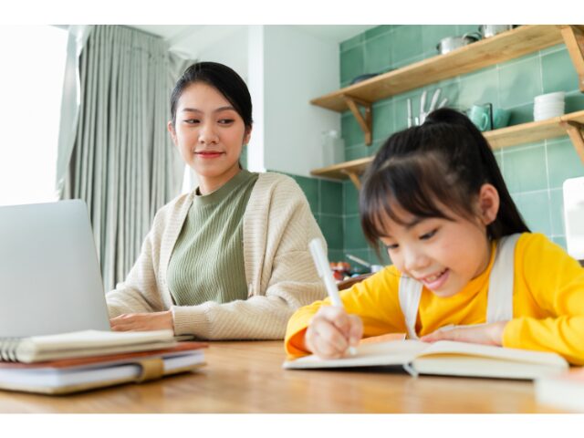 家で勉強している子供と見守る母