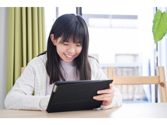 笑顔でタブレットをみている女の子